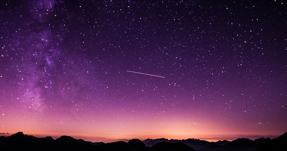 Starry night sky with the Milky Way arching over dark Andean hills